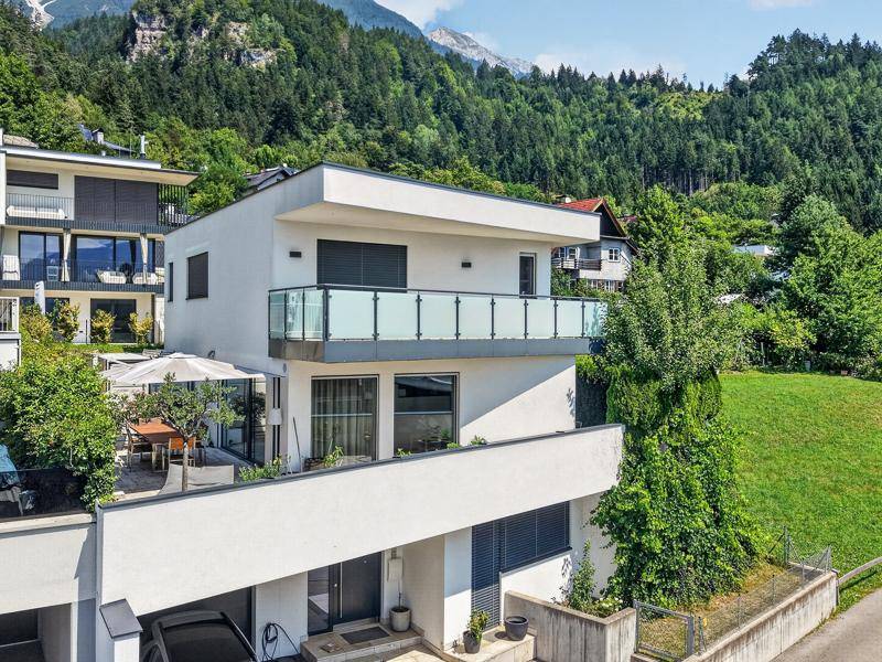 Modernes Wohnhaus mit Balkonen und Terrasse in idyllischer Hanglage mit beeindruckendem Bergblick.