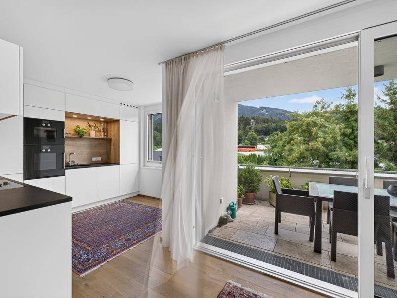 Helle Küche mit modernen Geräten und direktem Zugang zu einer sonnigen Terrasse mit Bergblick.