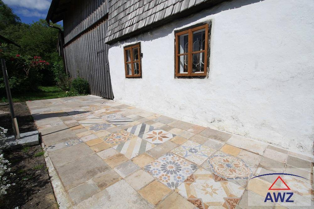 Originelle Terrasse mit gemusterten Fliesen und weiß getünchter Hauswand, ideal für Entspannung.