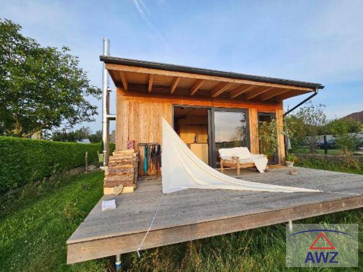 Modernes Holzhaus mit großer Holzterrasse, Hängematte und Blick auf die umliegende Natur.