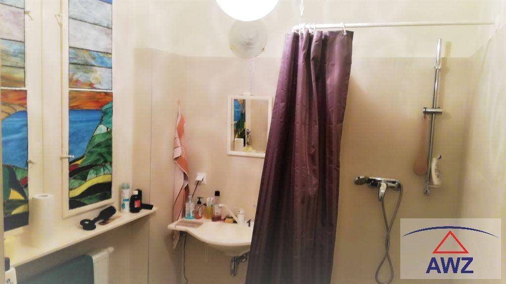 Badezimmer mit Waschbecken, Dusche und einem Fenster mit farbigem Glas.