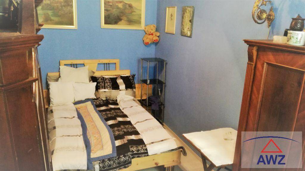Schlafzimmer mit Holzbett, blauen Wänden und traditionellen Bildern an der Wand.