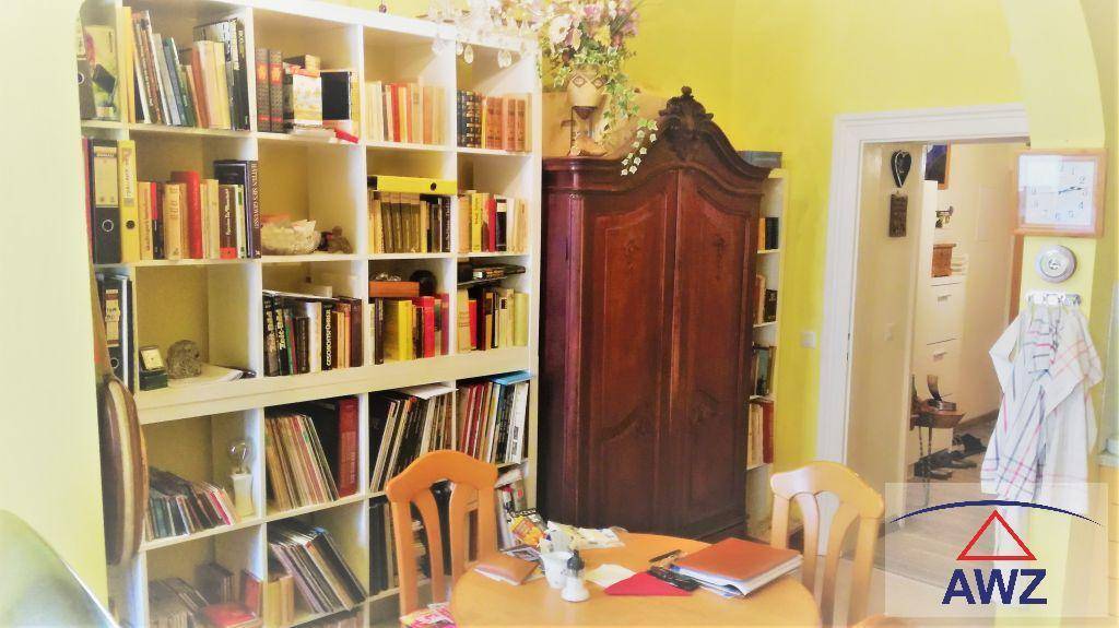 Gemütliches Arbeitszimmer mit Bücherregalen, einem antiken Schrank und gelben Wänden.