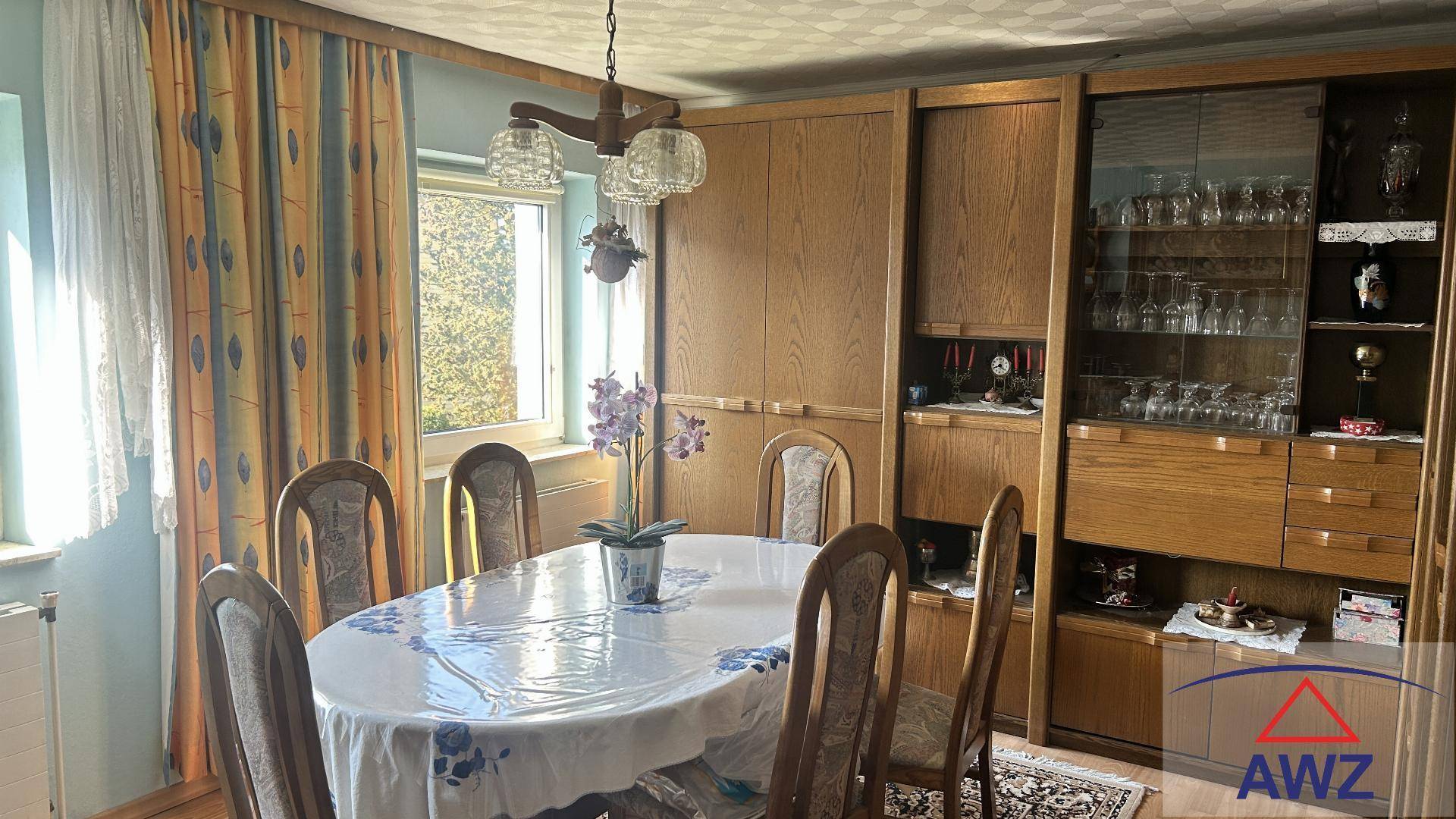 Gemütliches Esszimmer mit ovalem Holztisch, passenden Stühlen und einem großen Holzschrank.
