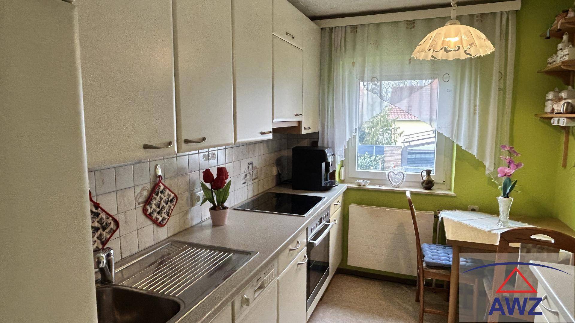 Helle Küche mit weißen Schränken, integrierten Geräten und einem kleinen Essbereich am Fenster.