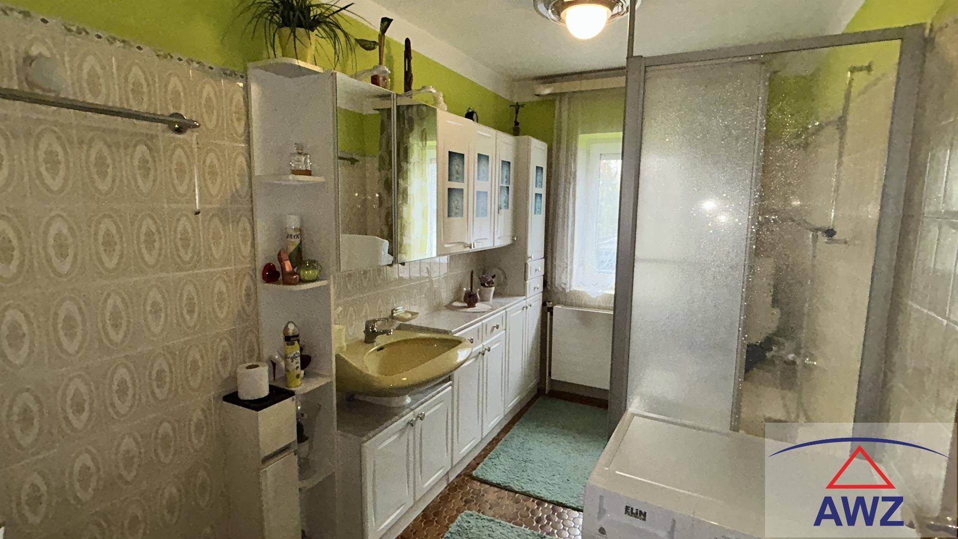 Badezimmer mit Duschkabine, Waschbecken und hellgrünen Fliesen an den Wänden.
