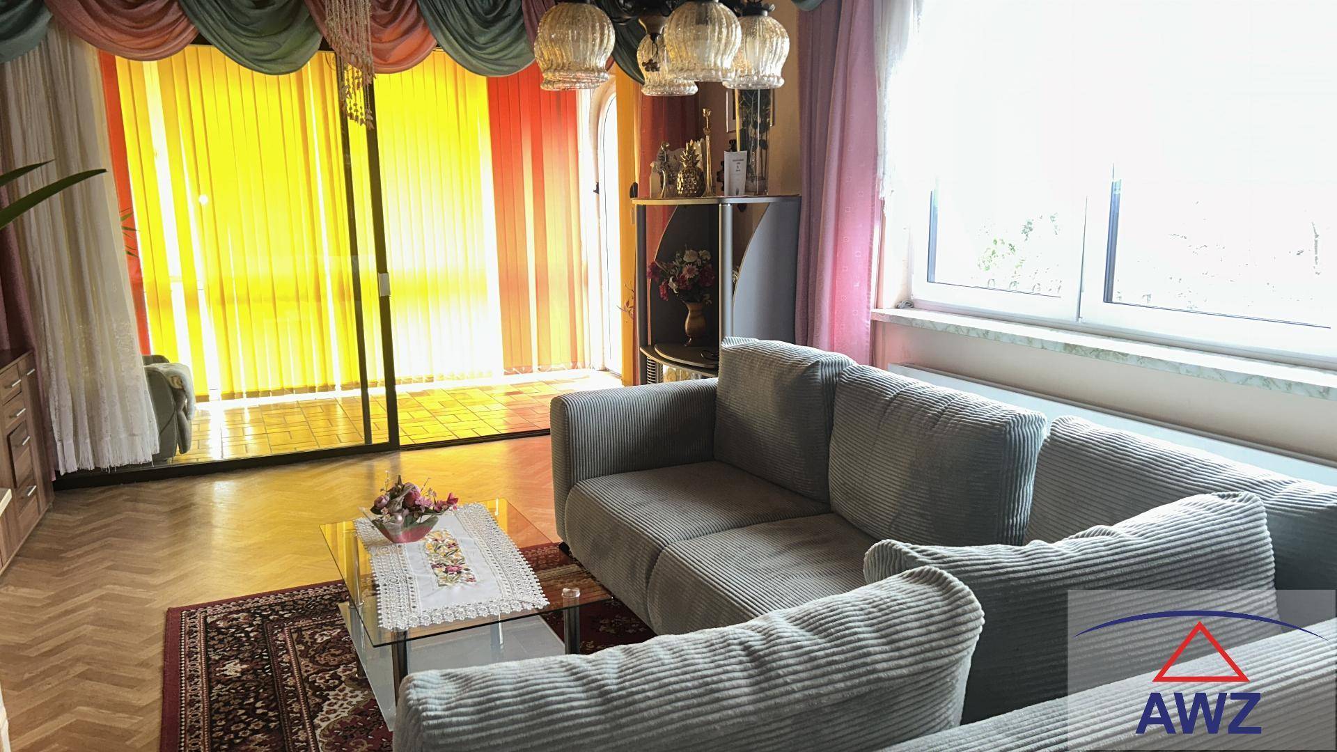 Geräumiges Wohnzimmer mit bequemen Sofas, Parkettboden und großen Fenstern mit Blick ins Grüne.