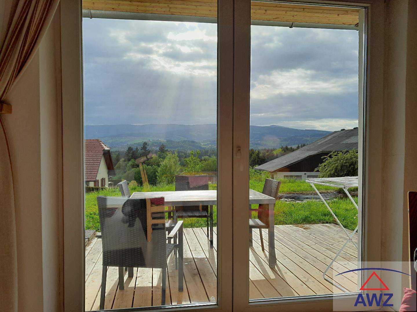 Blick aus dem Innenraum auf die Terrasse und die umliegende Berglandschaft.