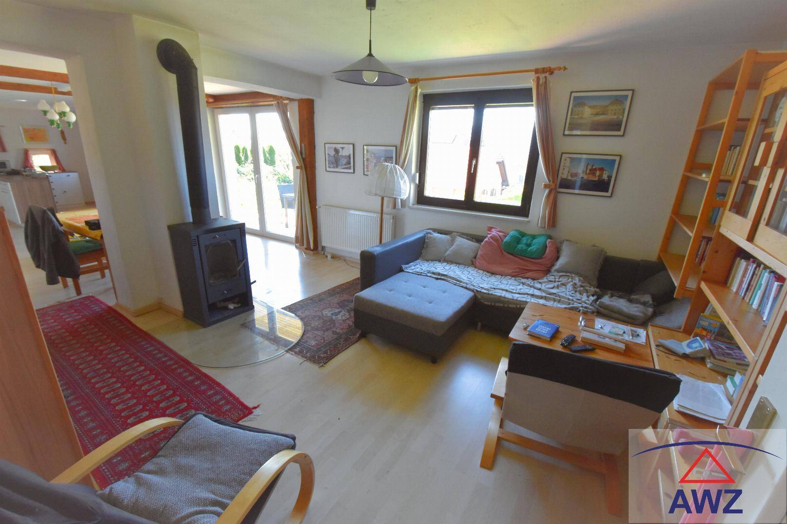 Gemütliches Wohnzimmer mit Kaminofen, Sofa und Blick ins Grüne.