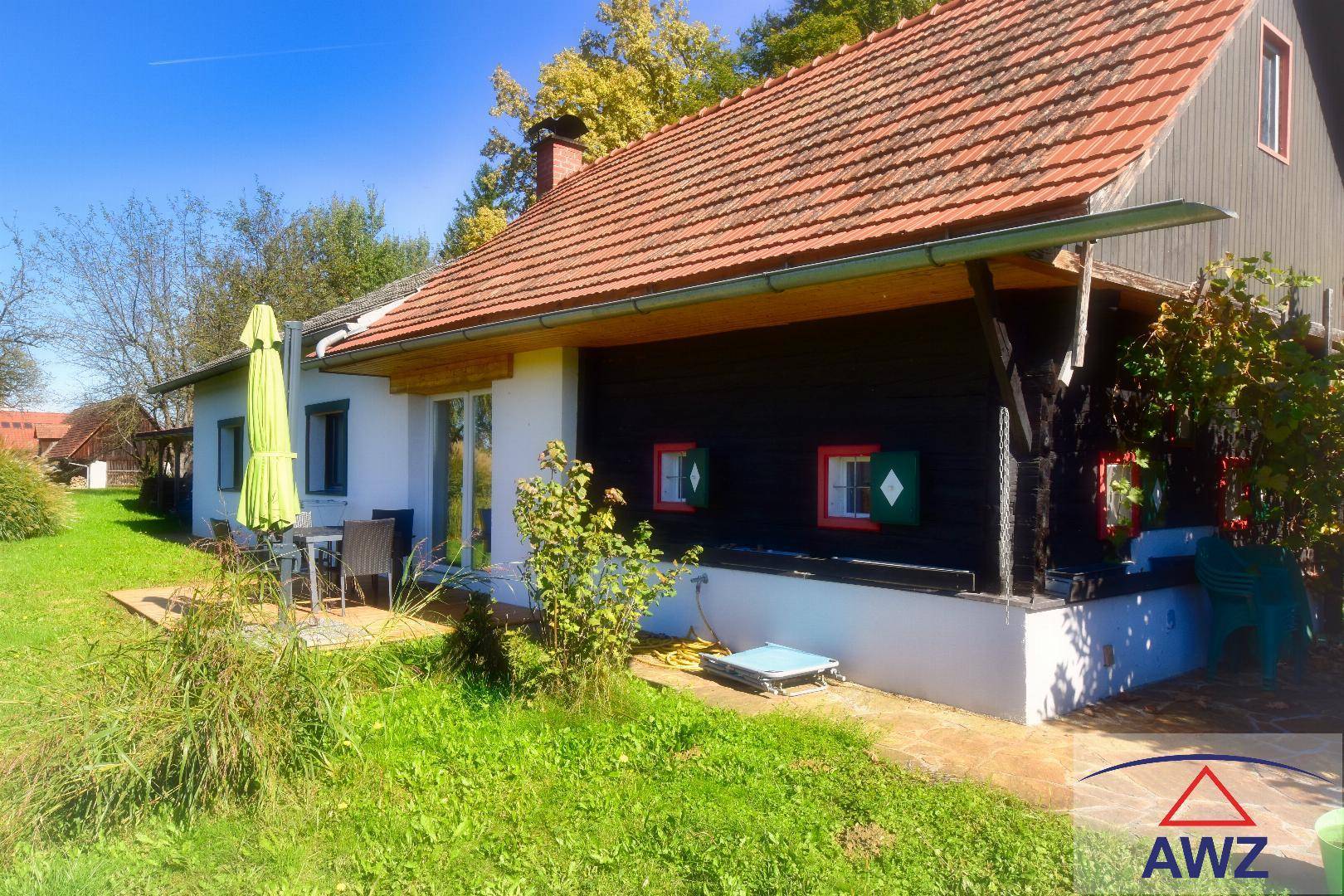 Charmantes Landhaus mit rotem Ziegeldach, kleiner Terrasse und großem Garten.