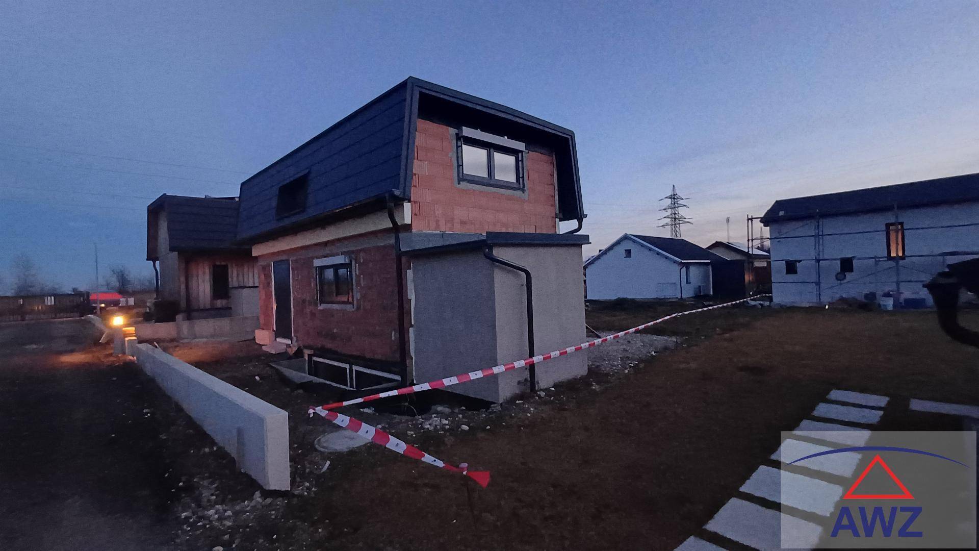 Seitenansicht des Neubauhauses im Rohbau mit Dach und umgebender Baustelle.