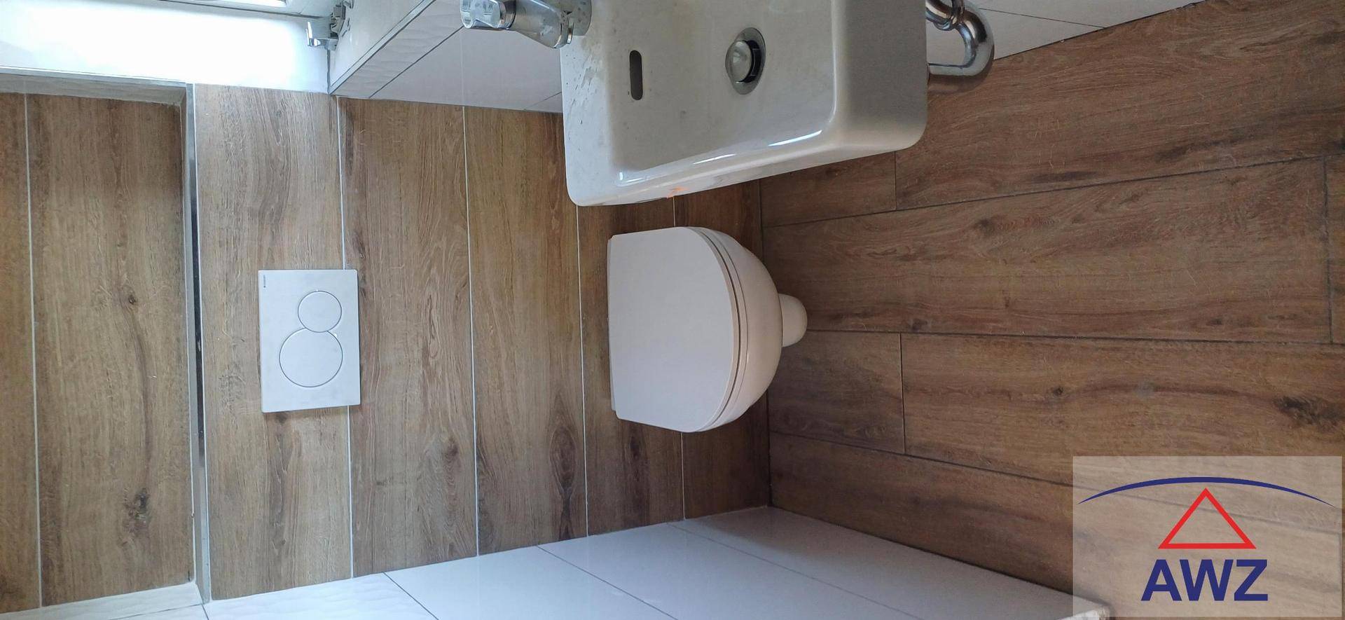 Kleines WC mit Holzoptik-Wandfliesen, wandhängendem WC und modernem Waschbecken.