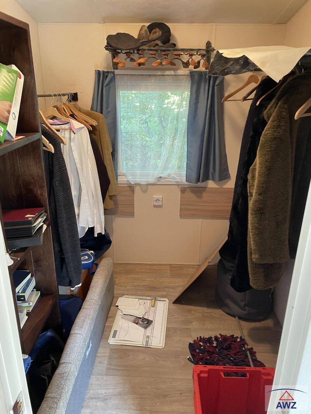 Kleiner Raum mit Kleiderstangen und Regalen, der als Abstell- oder Ankleidezimmer dient.