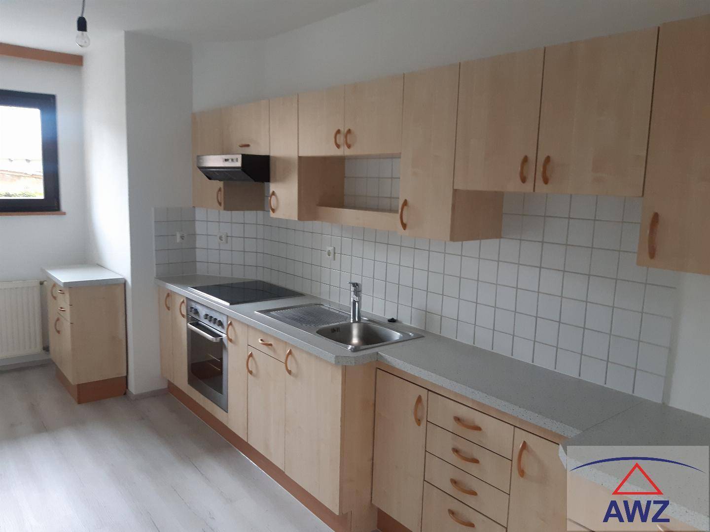 Funktionale Küche mit hellen Holzschränken, integrierten Geräten und Fenster.