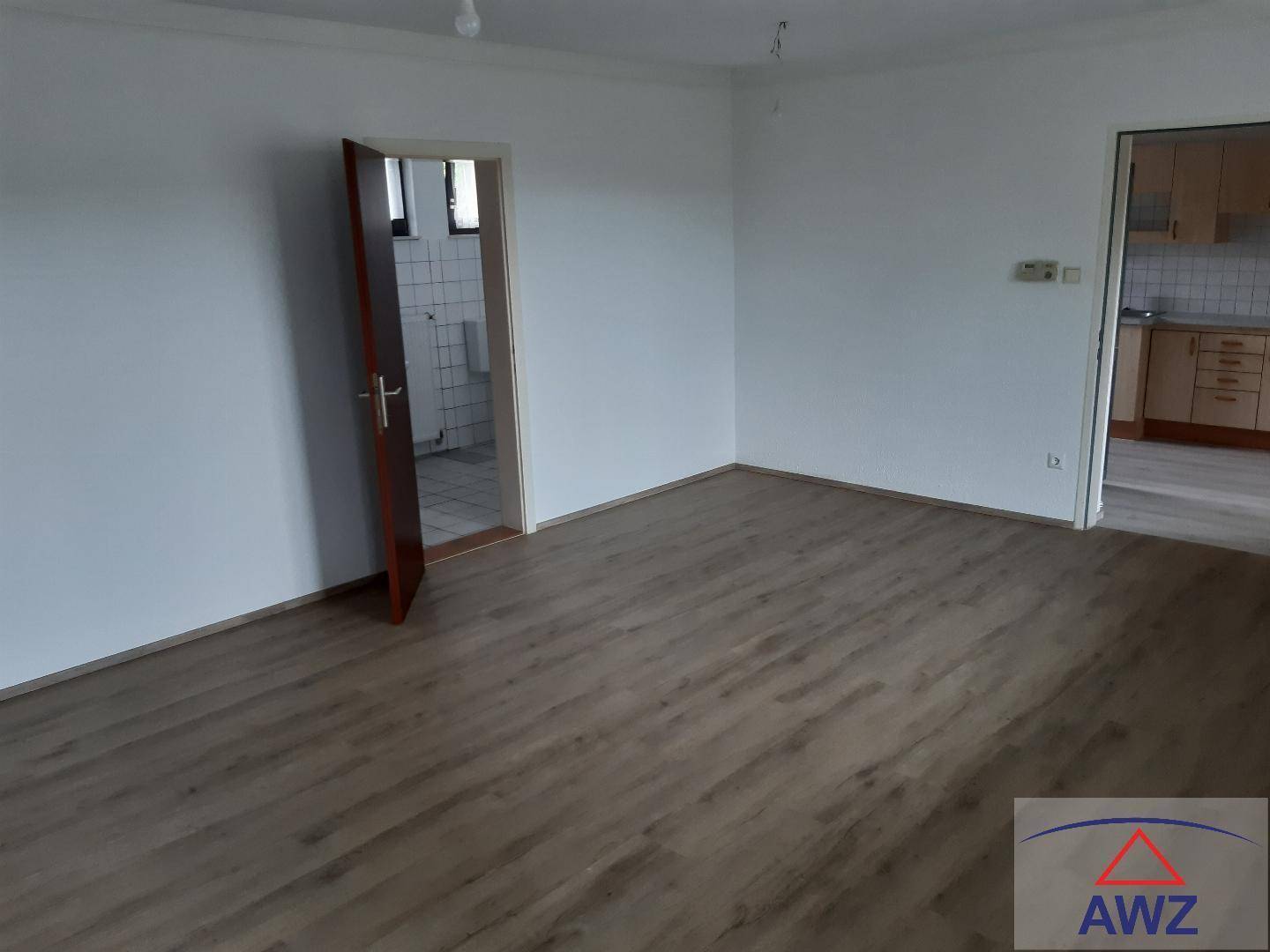 Leerer Raum mit neuem Laminatboden und Zugang zu weiteren Zimmern.