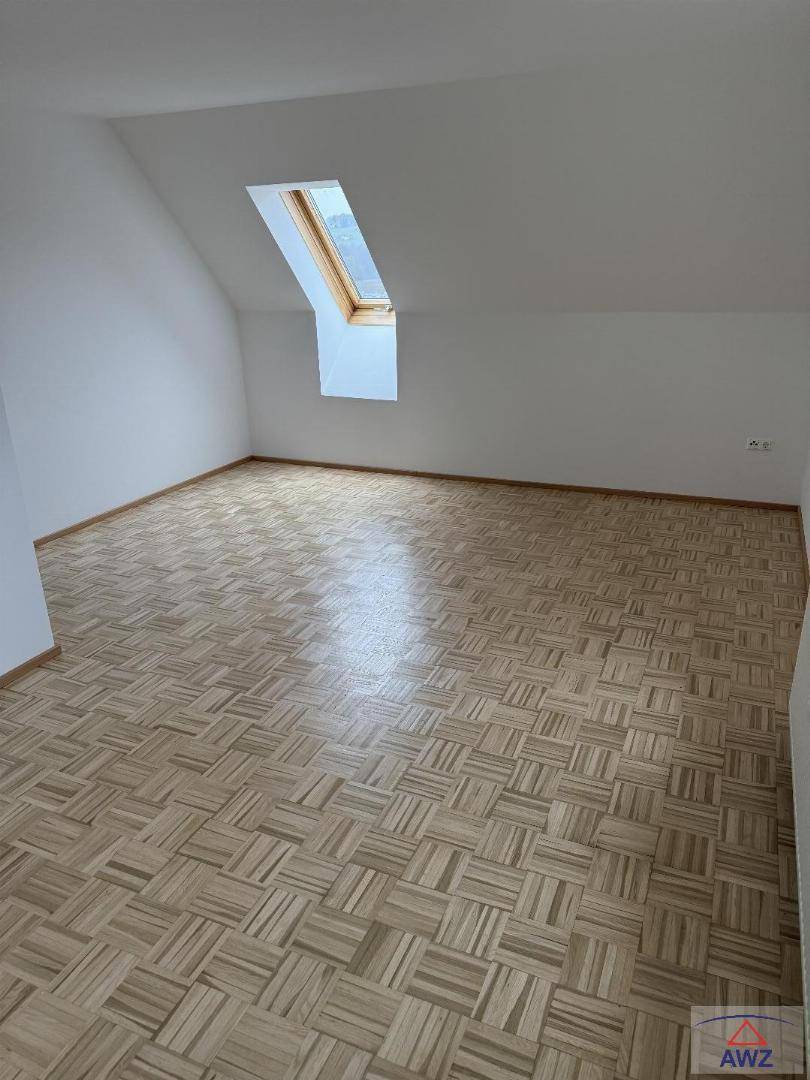 Helles Zimmer im Dachgeschoss mit Parkettboden und Dachfenster für viel Tageslicht.