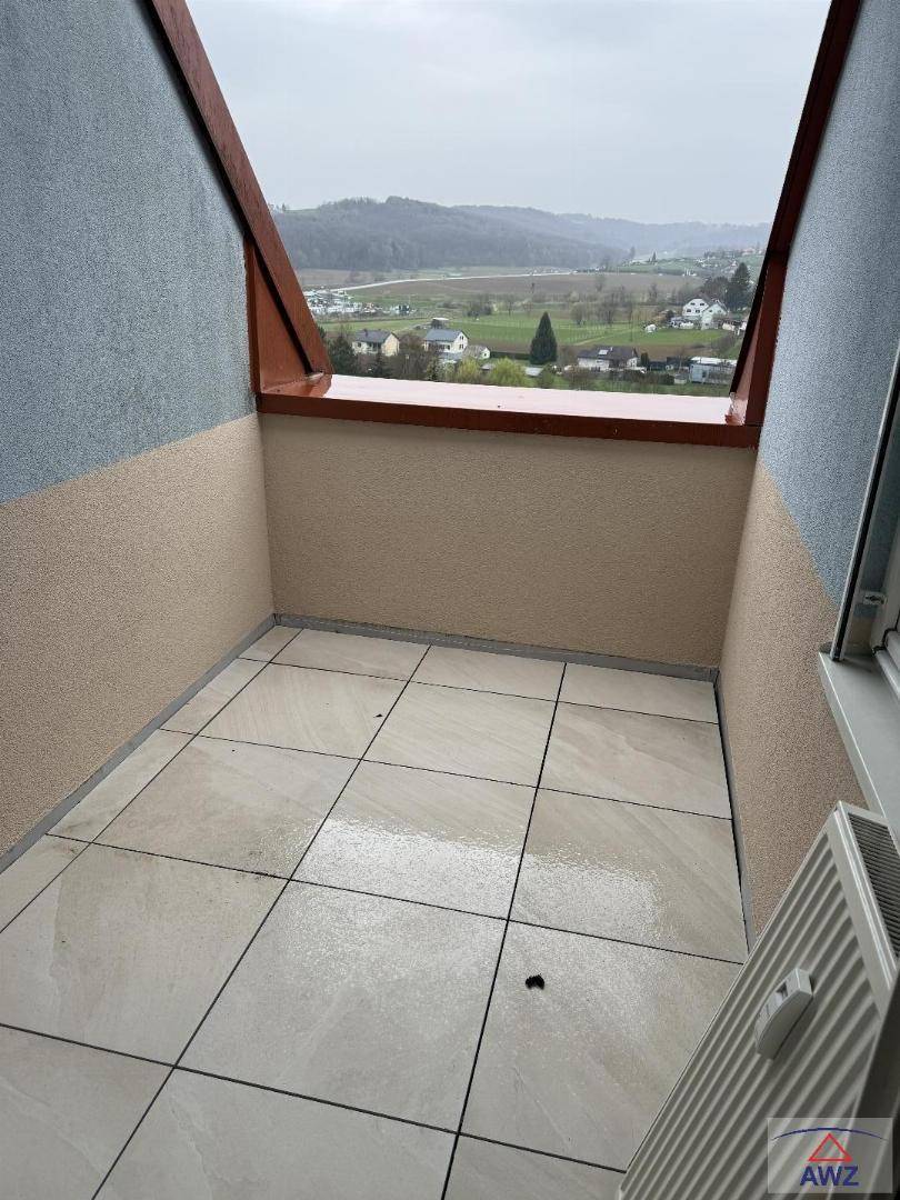 Kleiner Balkon mit Fliesenboden und schöner Aussicht auf die grüne Umgebung.