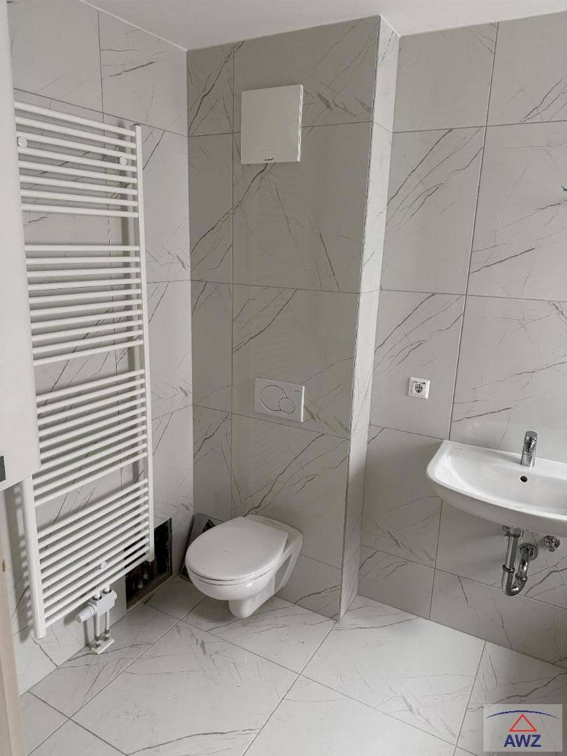 Modernes Badezimmer mit hellen Fliesen, wandhängendem WC und beheiztem Handtuchhalter.