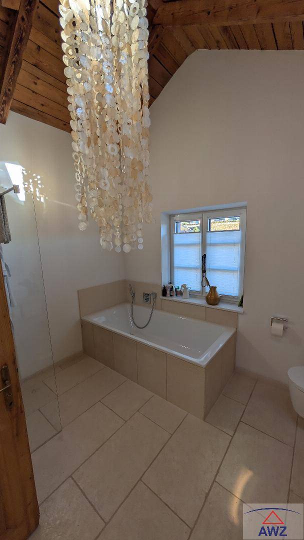 Helles Badezimmer mit Badewanne, Dachschräge und Holzbalken.