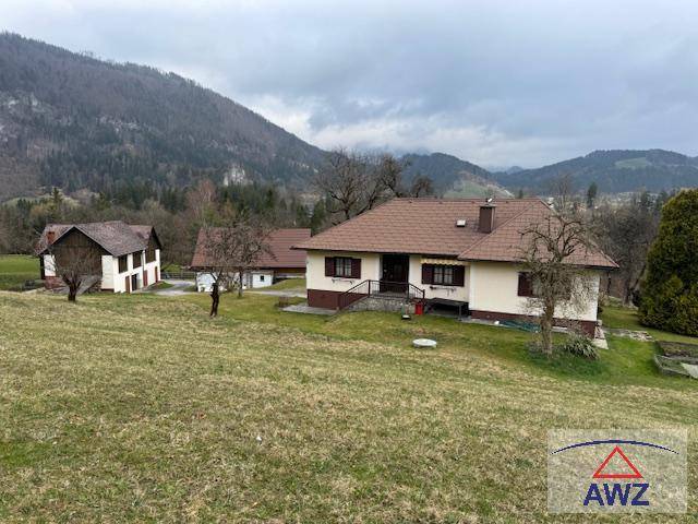 Landhaus mit braunem Ziegeldach und heller Fassade, umgeben von Wiesen und Bäumen in ländlicher Umgebung.