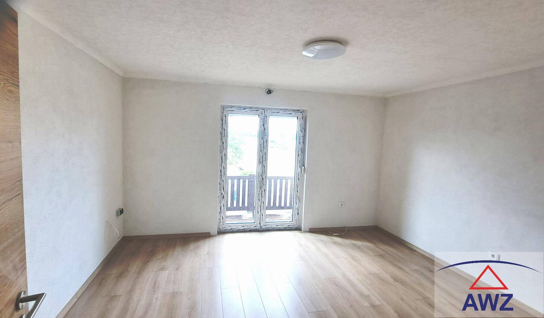 Leerer, heller Raum mit Laminatboden und Zugang zu einem französischen Balkon.