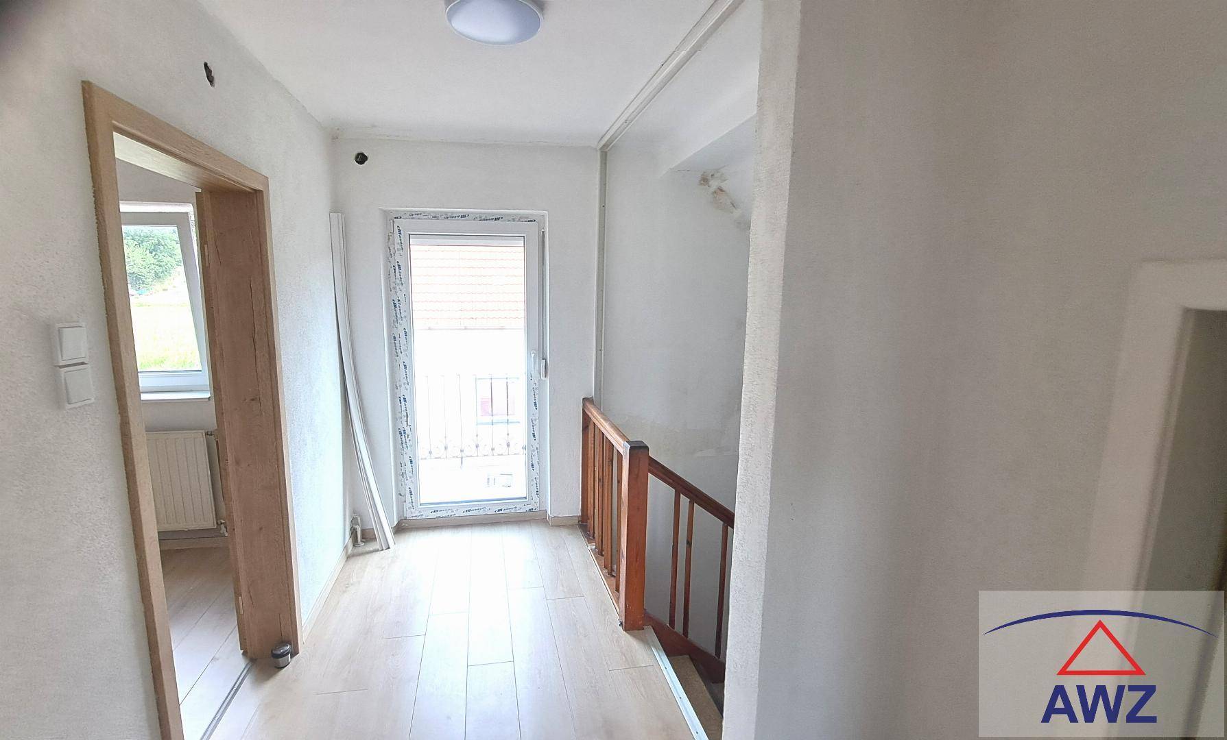 Heller Flur mit Laminatboden, Treppenzugang und einem Fenster für natürliches Licht.