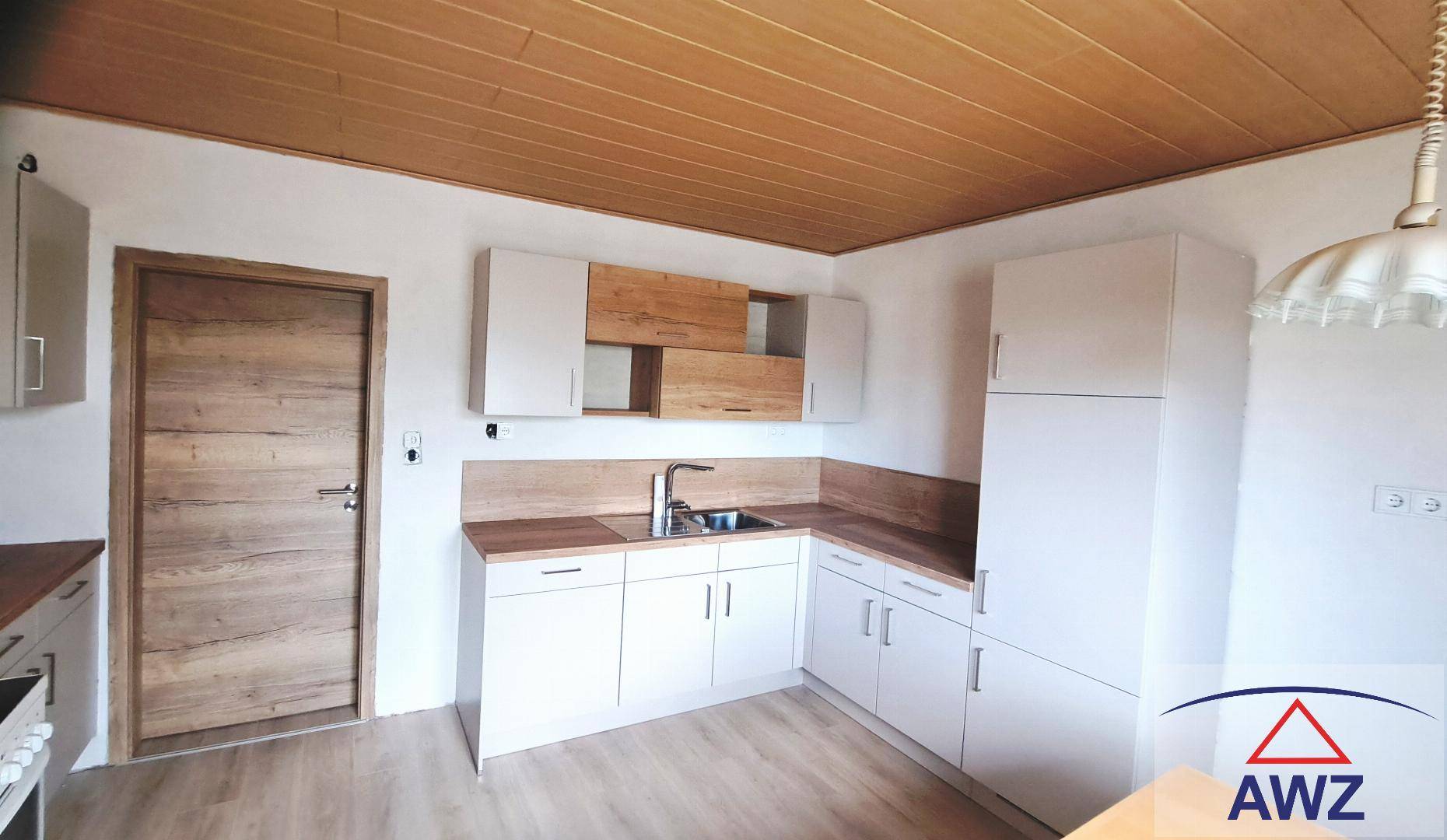 Helle Küche mit weißen Schränken, Holzarbeitsplatten, Laminatboden und einer Holzdecke.