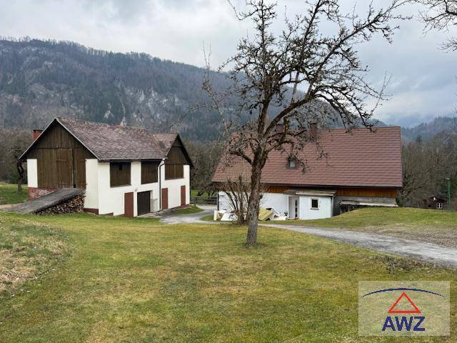 Zwei traditionelle Gebäude mit Holzelementen und braunen Dächern, eingebettet in eine ländliche Berglandschaft.