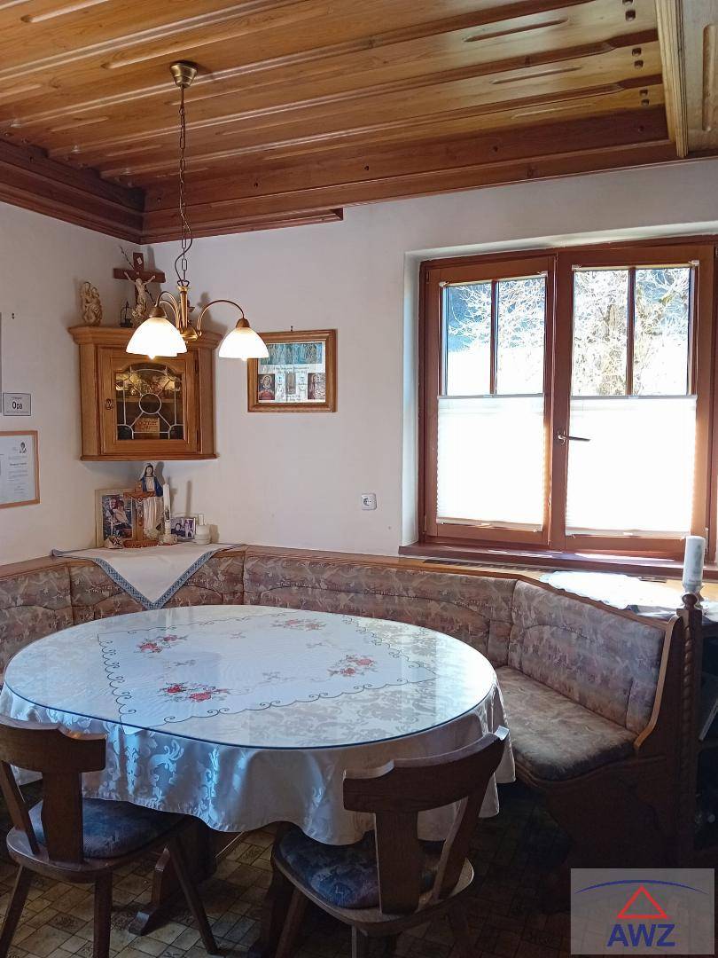 Gemütlicher Essbereich mit Holztäfelung an Decke und Wänden, traditionellen Möbeln und Blick ins Grüne.