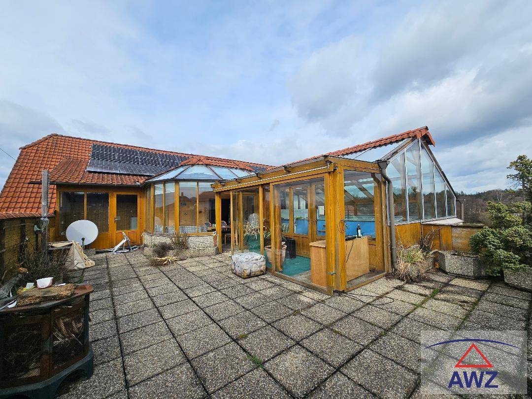 Große gepflasterte Terrasse mit angrenzendem Wintergarten und Solaranlage auf dem Dach.
