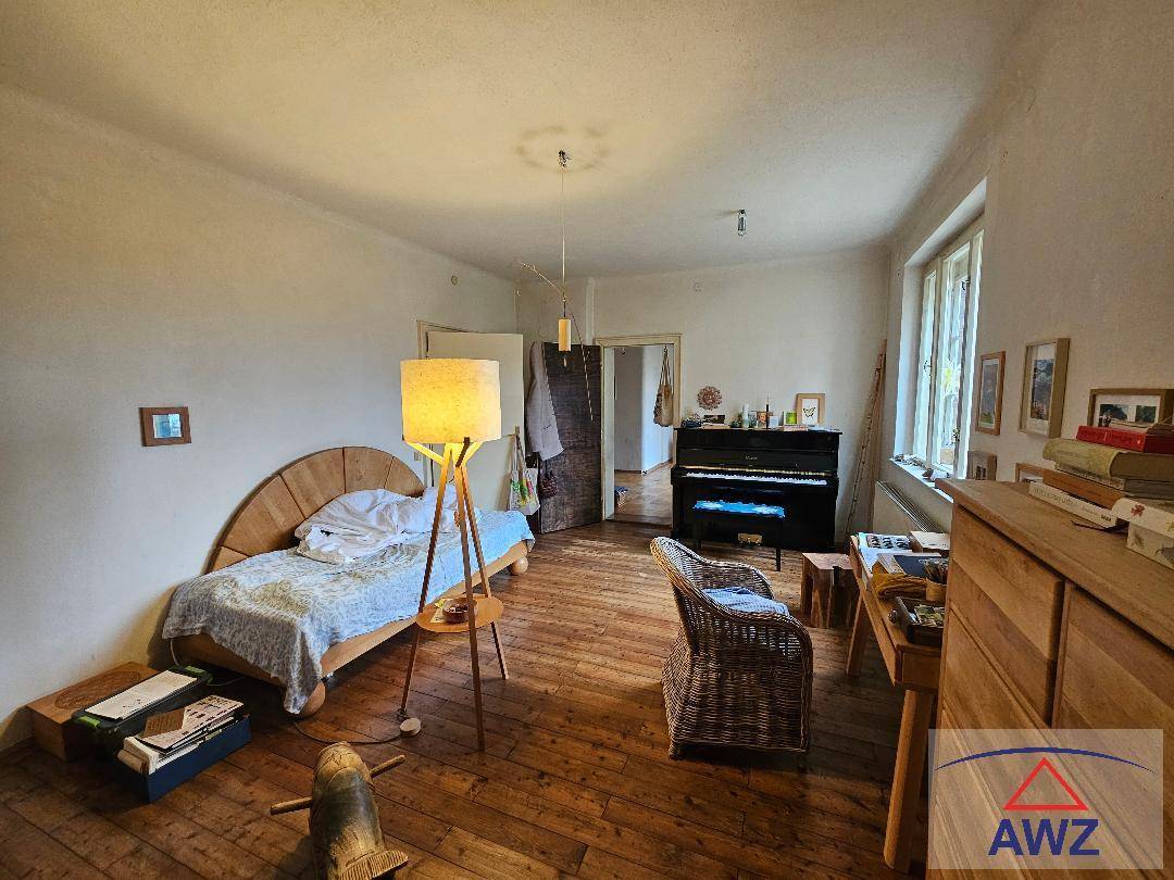 Schlafzimmer mit Holzbett, Klavier und Kommode, das einen rustikalen Charme besitzt.