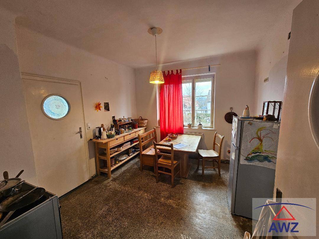 Wohnküche mit Esstisch, Kühlschrank und Fenster, die eine gemütliche Atmosphäre schafft.