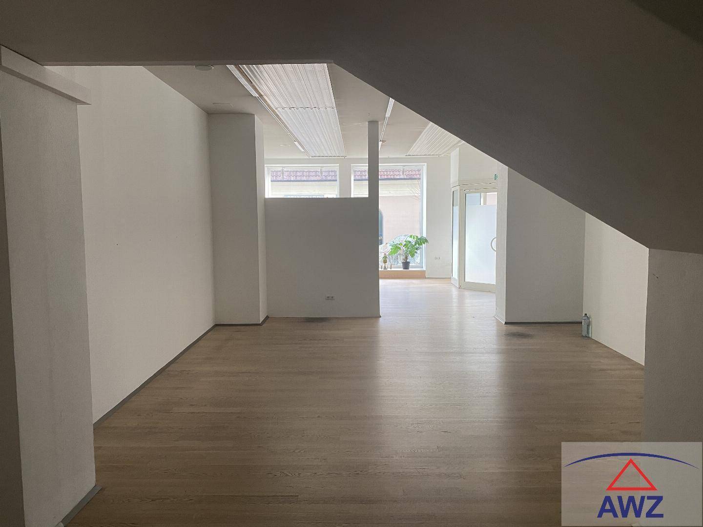 Offener Innenraum mit viel Tageslicht und durchgehendem Holzboden.
