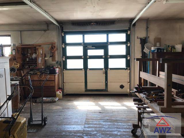 Geräumige Garage oder Werkstatt mit großem Tor und Holzboden, ideal für Hobby und Lagerung.