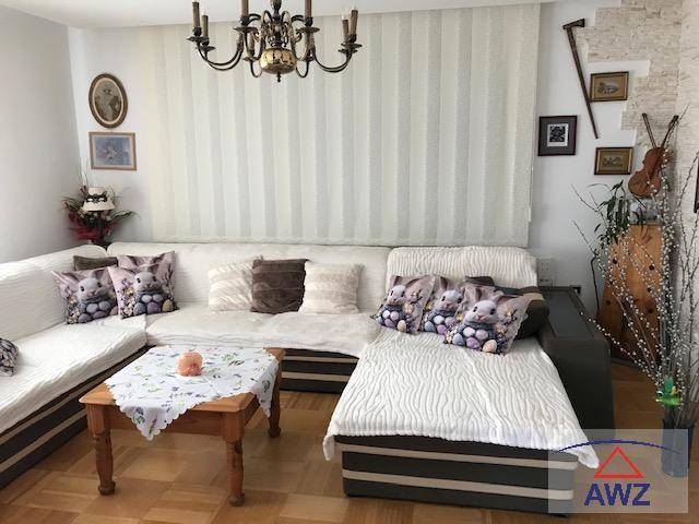 Helles Wohnzimmer mit großem Ecksofa, Holzboden und klassischem Kronleuchter.