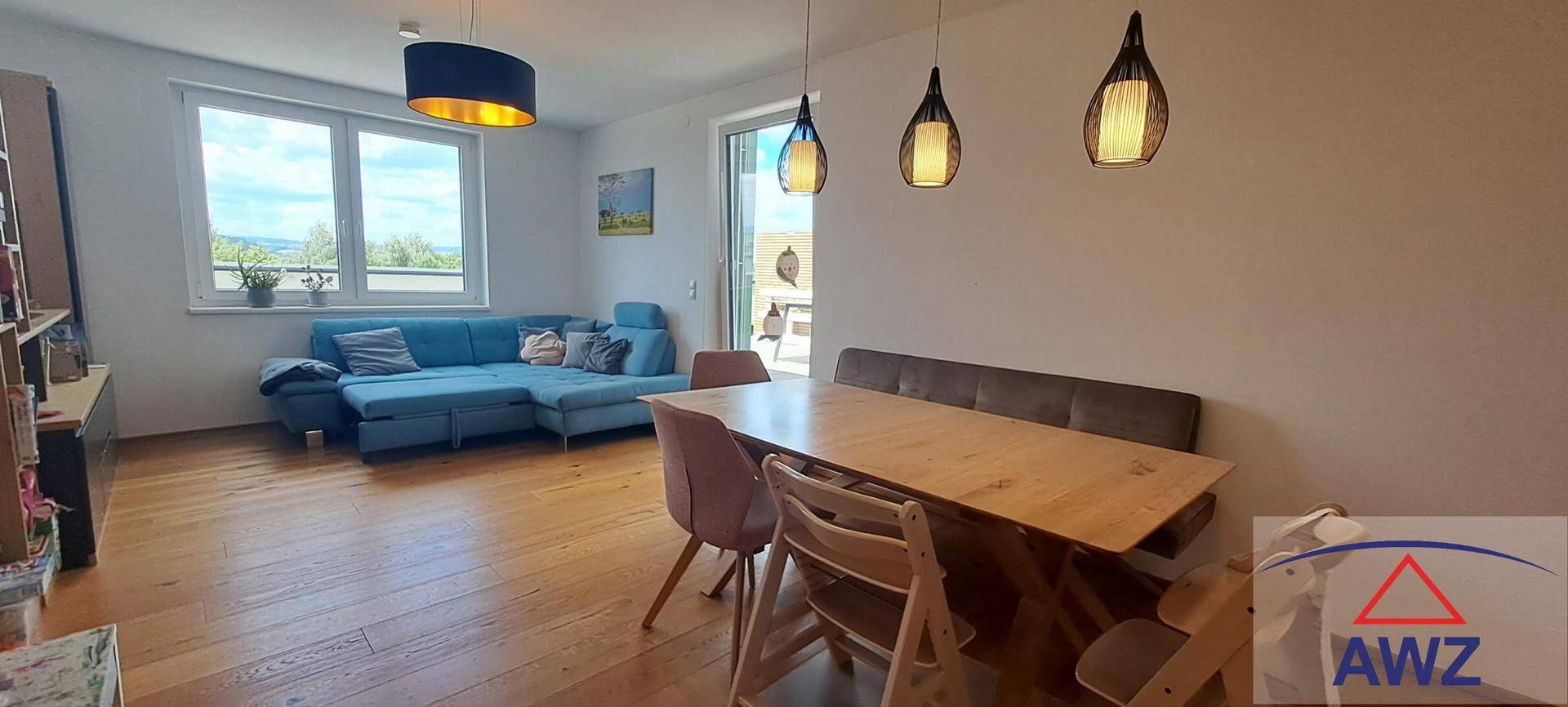 Heller offener Wohn-Essbereich mit Holzboden, bequemer Couch und modernem Esstisch.