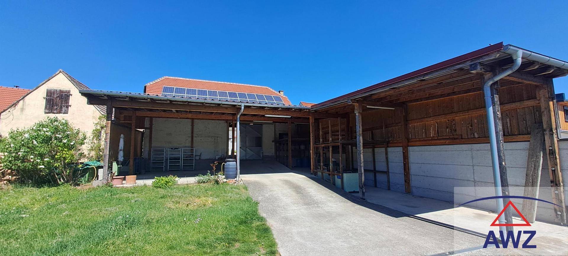 Außenansicht des Anwesens mit Carport, Zufahrt und Solaranlage auf dem Dach.
