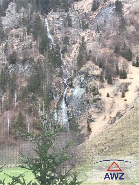Beeindruckender Wasserfall, der sich über eine felsige Bergwand in einer grünen Landschaft ergießt.