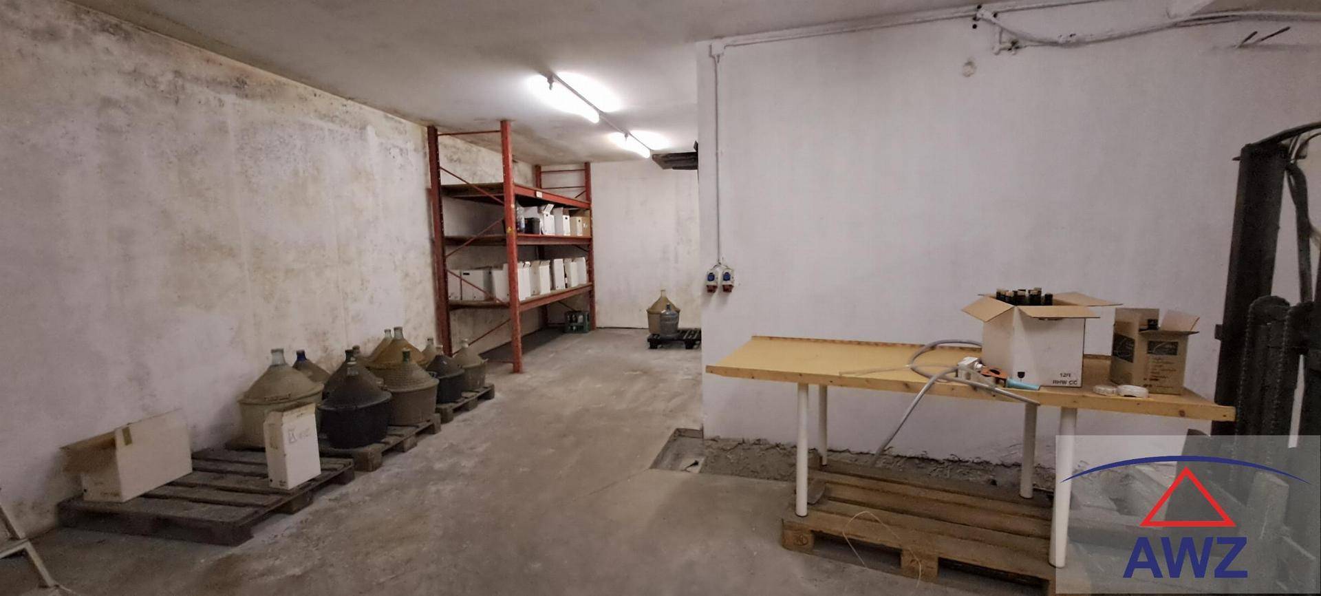 Geräumiger Lagerraum mit Regalen, Betonboden und verschiedenen Behältern.