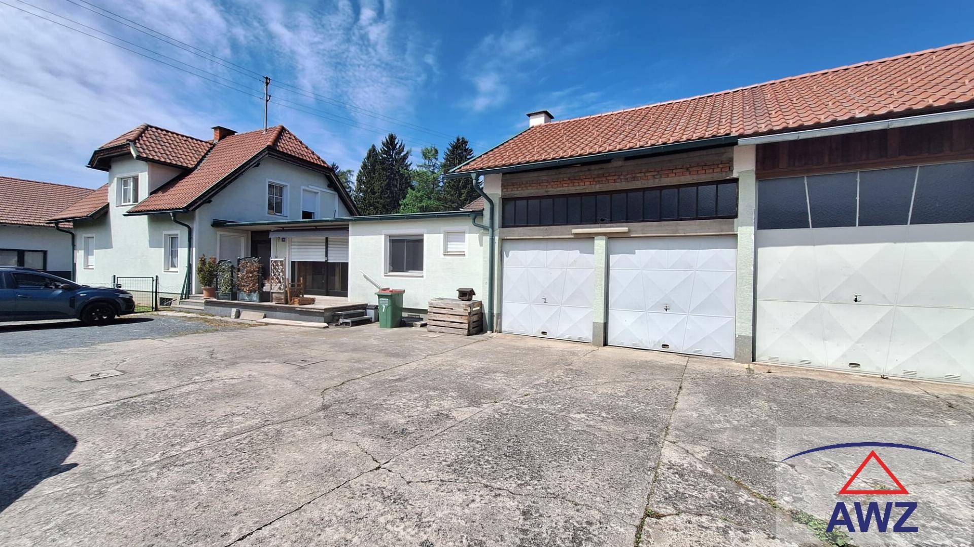 Rückansicht des Hauses mit angrenzender Garage und großem gepflasterten Hofbereich.