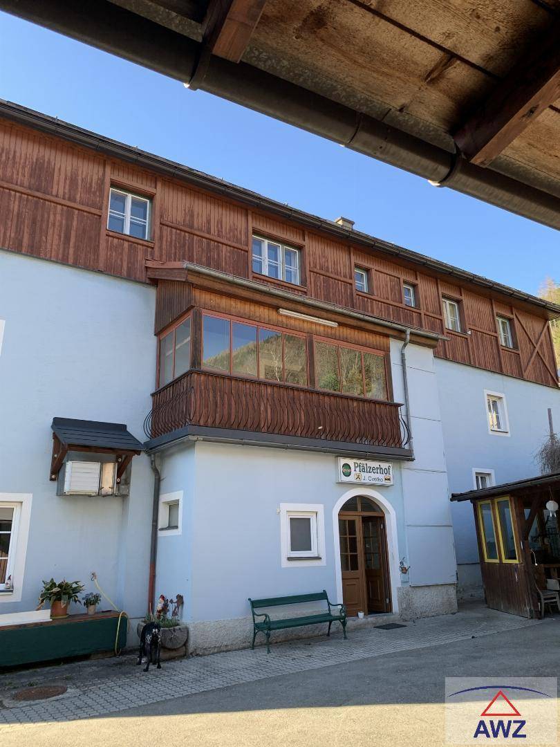 Fassade eines traditionellen Gebäudes mit hellblauer Wand, Holzelementen und einem verglasten Balkon.