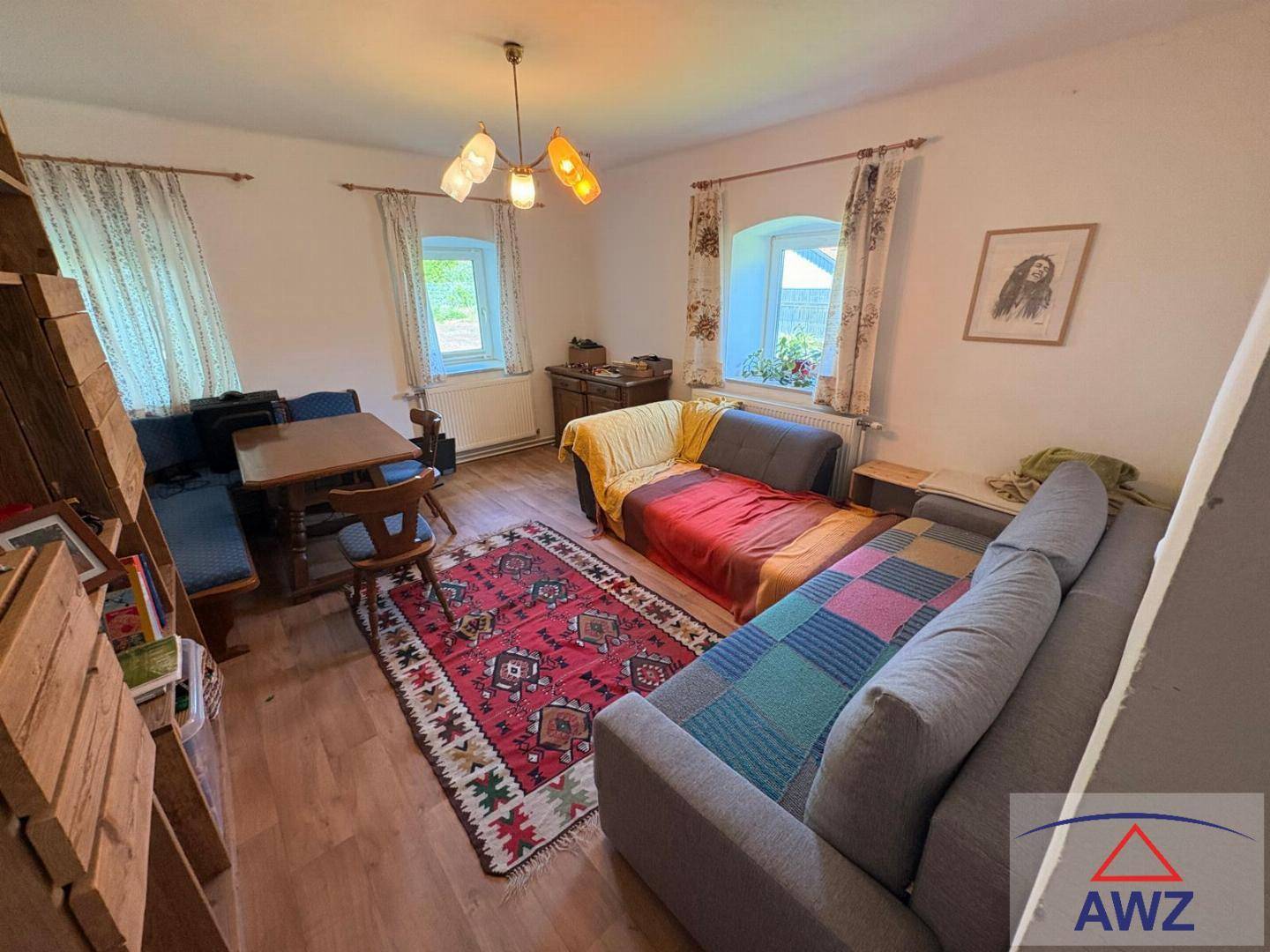 Gemütlicher Wohn-Essbereich mit Holzboden, Sofa, Esstisch und traditionellem Teppich.