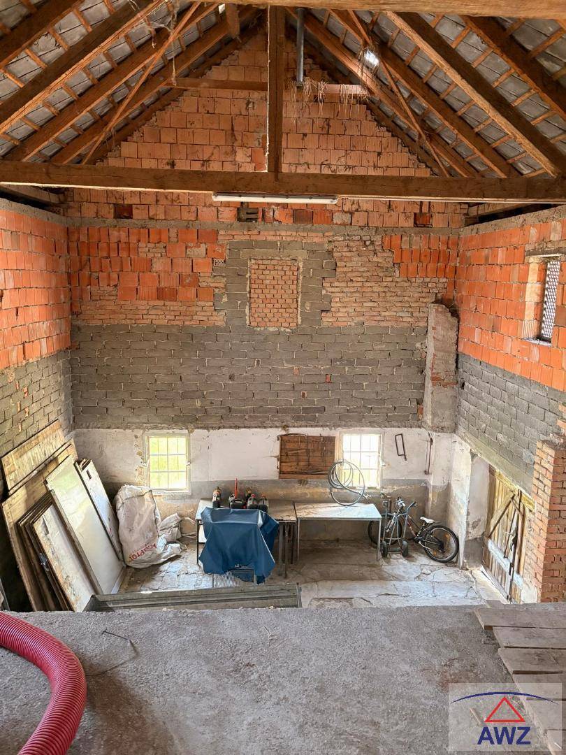 Unausgebauter Dachboden oder Scheunenbereich mit sichtbaren Ziegelwänden und Holzbalken, bereit für den Ausbau.