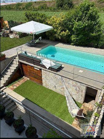 Außenbereich mit Swimmingpool, Liegefläche und Hängematte, umgeben von grüner Landschaft.