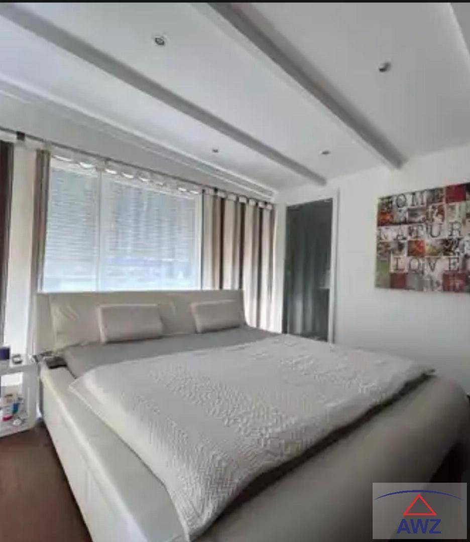 Helles Schlafzimmer mit großem Doppelbett, modernen Deckenleuchten und Kunst an der Wand.