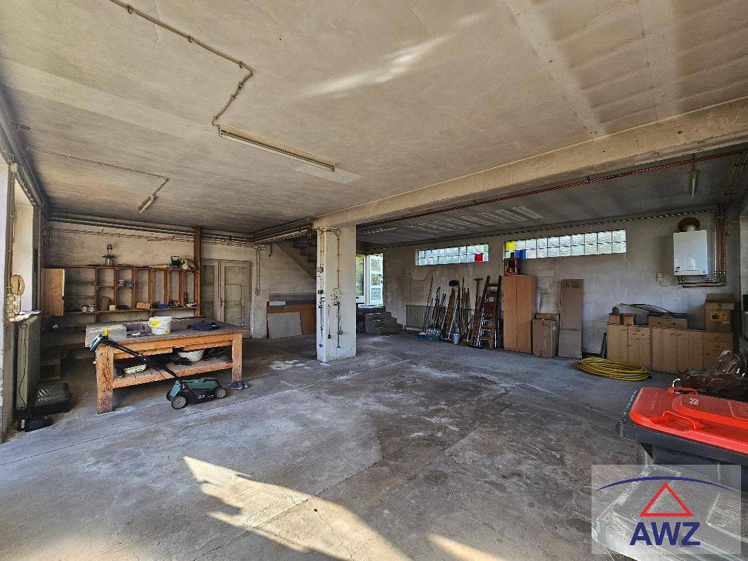 Geräumige Garage oder Werkstatt mit Betonboden, viel Stauraum und einem Warmwasserbereiter.