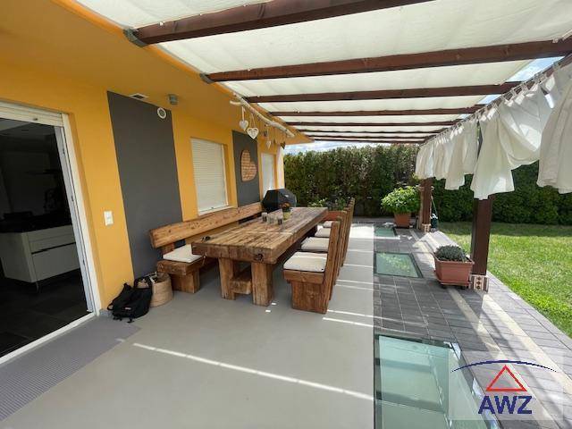 Große Terrasse mit rustikalem Holztisch und Pergola, ideal für Mahlzeiten im Freien.