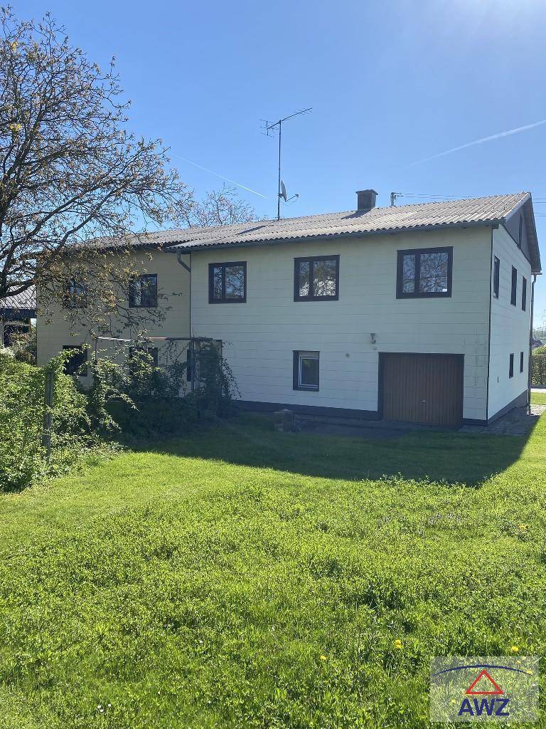 Rückansicht des Wohnhauses mit großem Garten, Garage und Satteldach an einem sonnigen Tag.