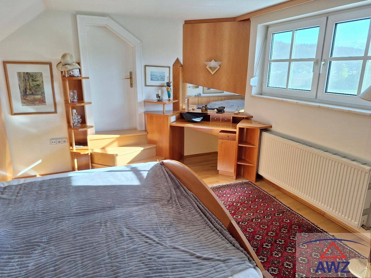 Gemütliches Schlafzimmer mit Holzboden, großem Fenster und einem Schminktisch mit Spiegel.