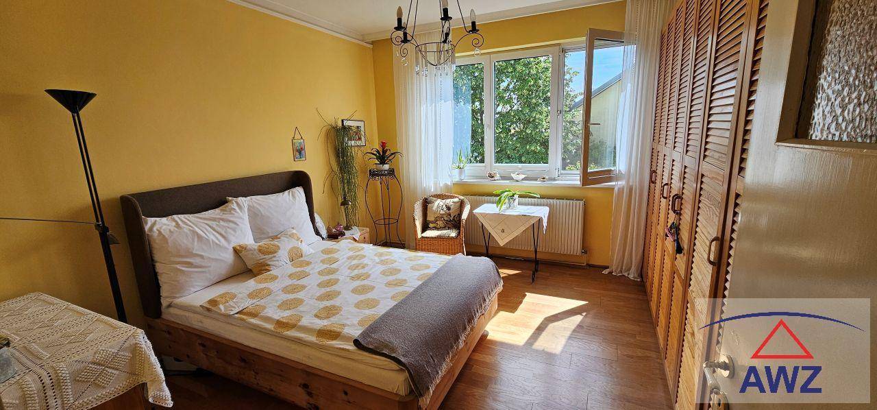 Gemütliches Schlafzimmer mit Doppelbett, großem Fenster und Holzschrank.